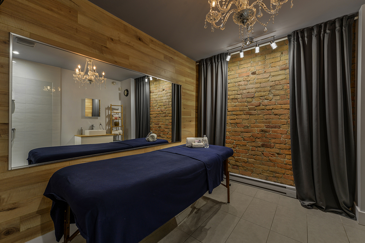 regular room from massage adagio with a massage table a mirror and a brick wall