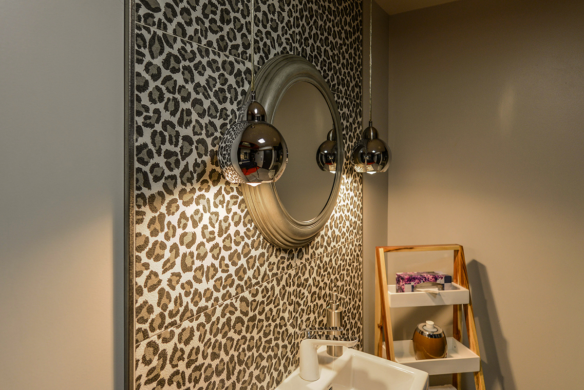 mirror and lights over a leopard ceramic wall and a sink