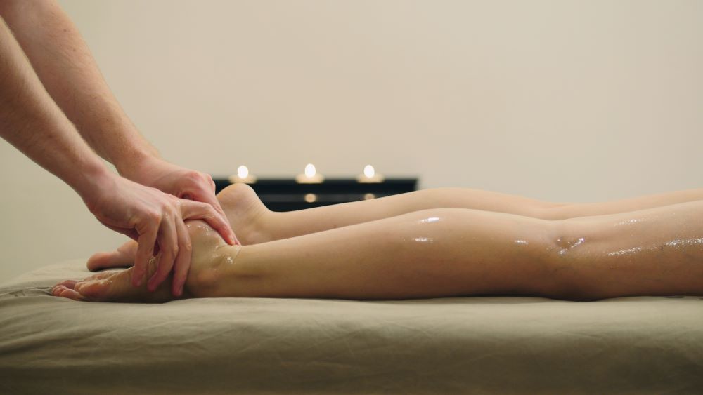 masseur qui procède à un massage des pieds érotique sur une femme